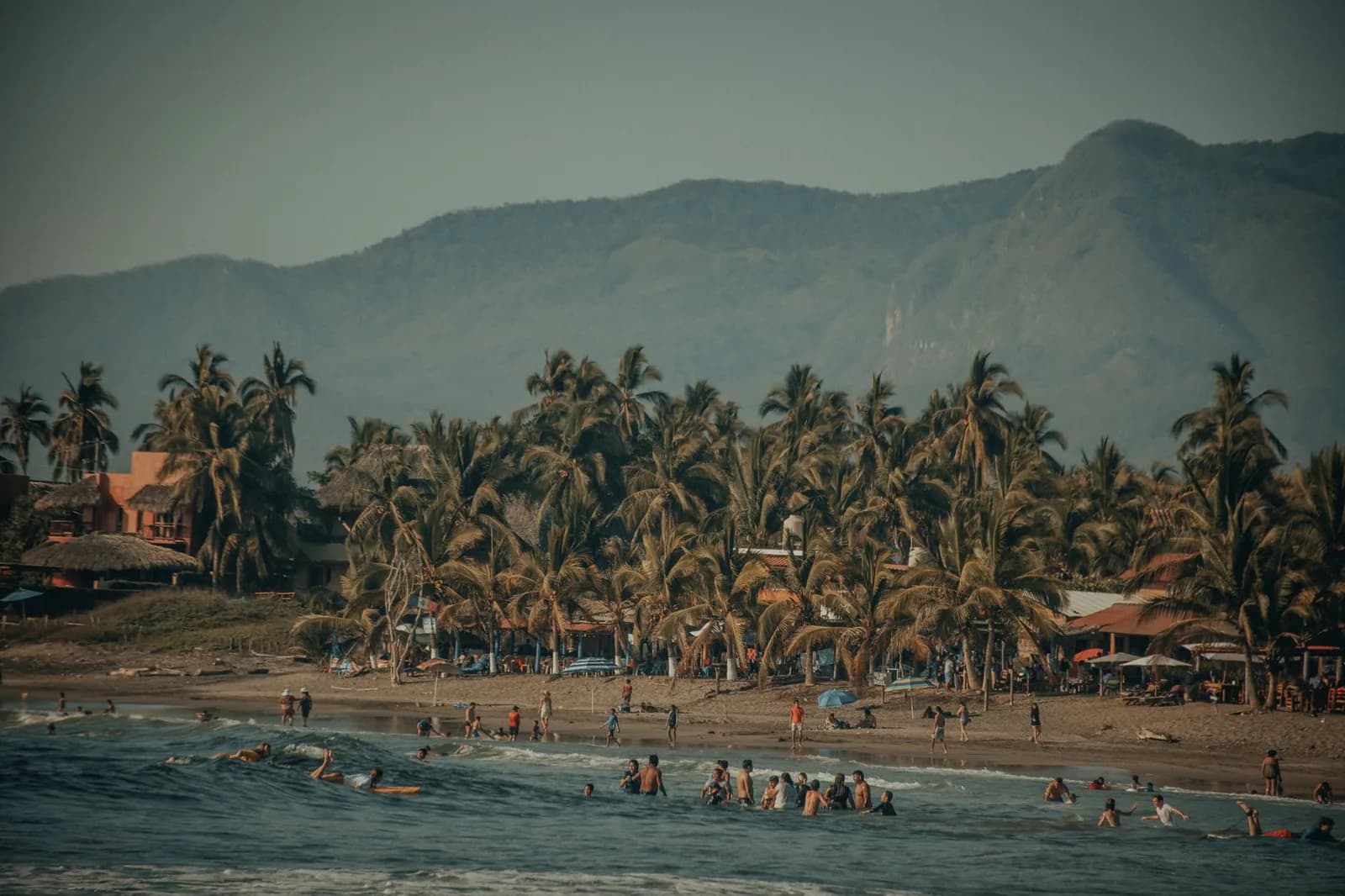 Plage bordée de palmiers au pied des montagnes dans la baie de Zihuatanejo, Guerrero