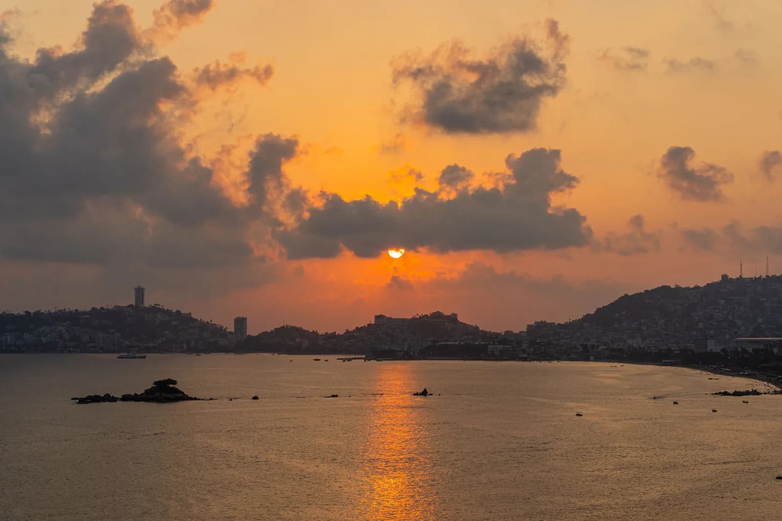 Coucher de soleil orangé sur la baie d'Acapulco et reflets sur l'eau