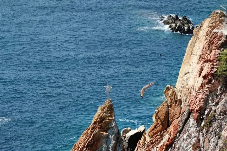 Clavadista en plein saut depuis la falaise de La Quebrada à Acapulco