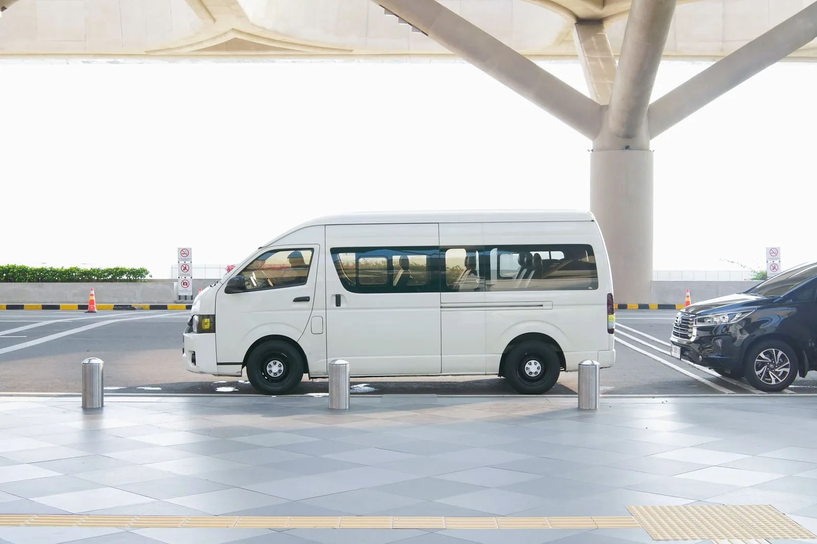 Van blanc de navette stationné devant le terminal d'un aéroport, prêt pour un transfert