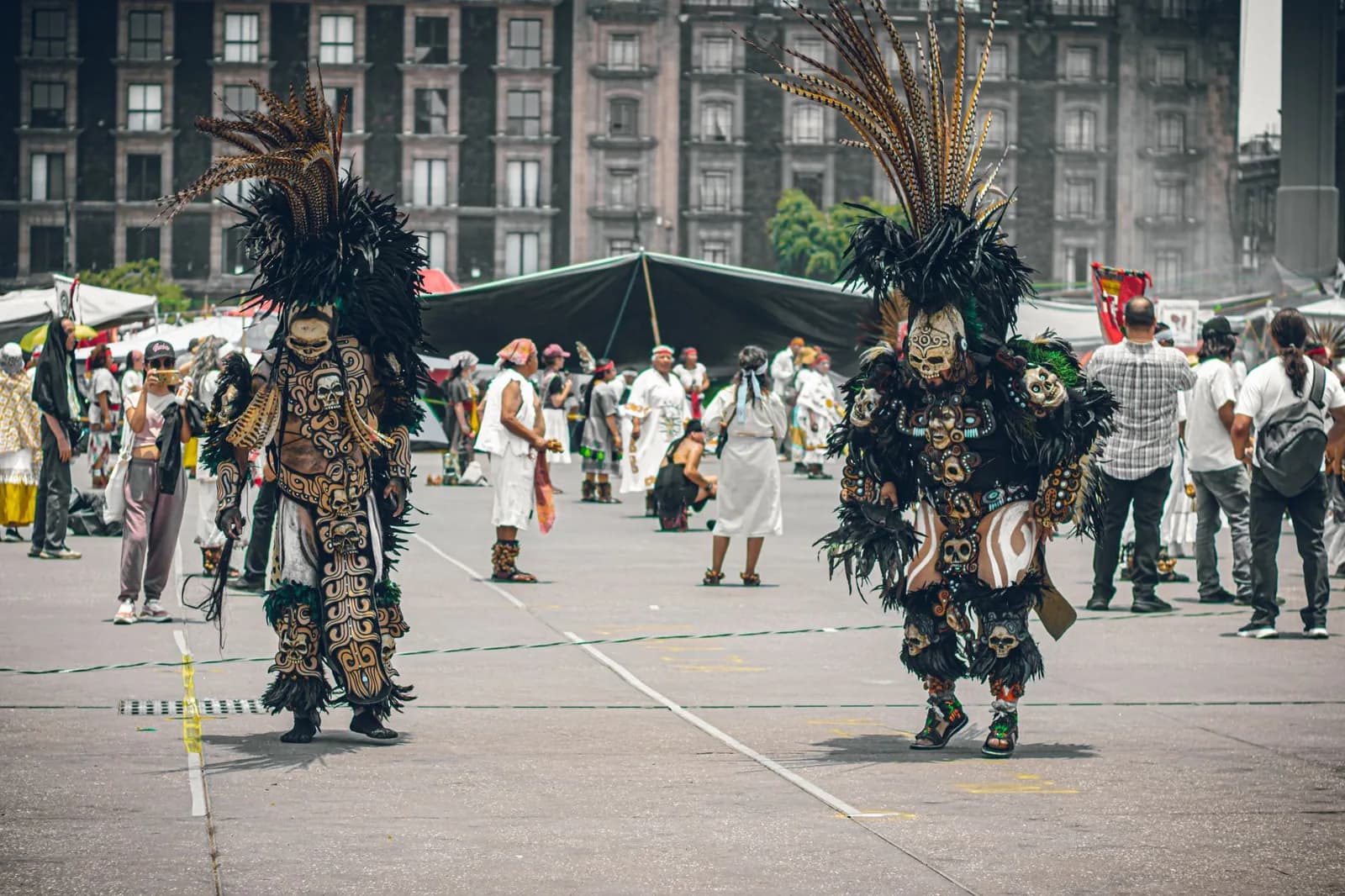 Deux danseurs aztèques en costume noir et doré, coiffés de plumes, sur une place du centre historique de Mexico