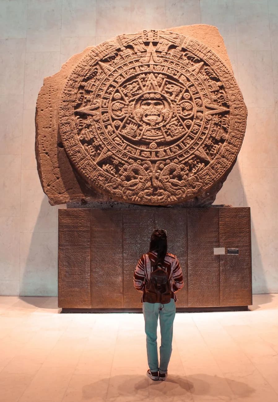 La Piedra del Sol, dite calendrier aztèque, sur son socle au Musée national d'anthropologie de Mexico, avec une visiteuse de dos