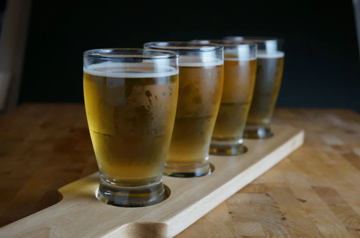 Planche de dégustation de bières artisanales servies en petits verres sur un comptoir en bois