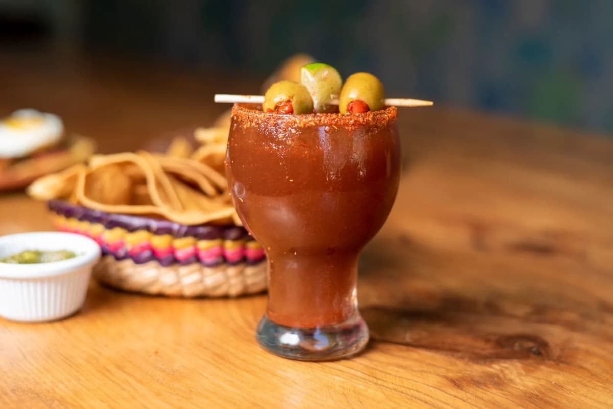 Michelada servie avec des chips de tortilla dans un bar mexicain, panier tressé aux couleurs vives