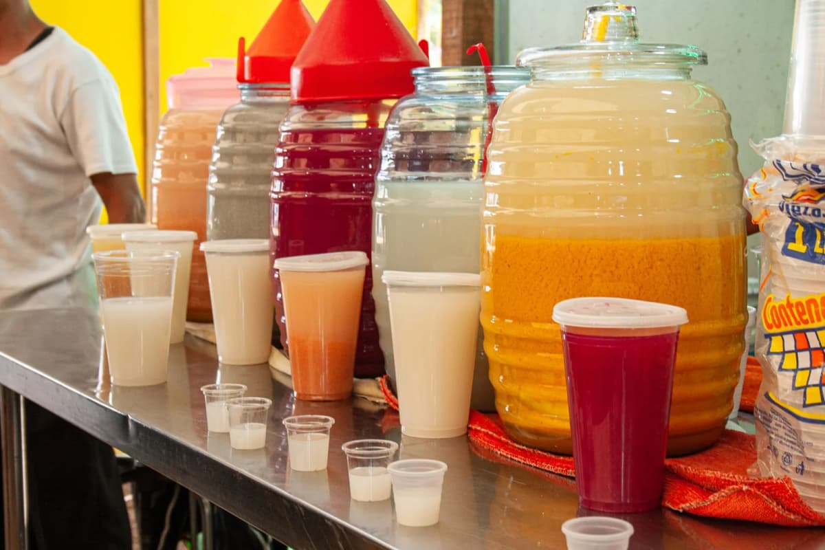 Vitroleros d'aguas frescas de jamaica, horchata et tamarindo servies en gobelets sur un stand de marché mexicain