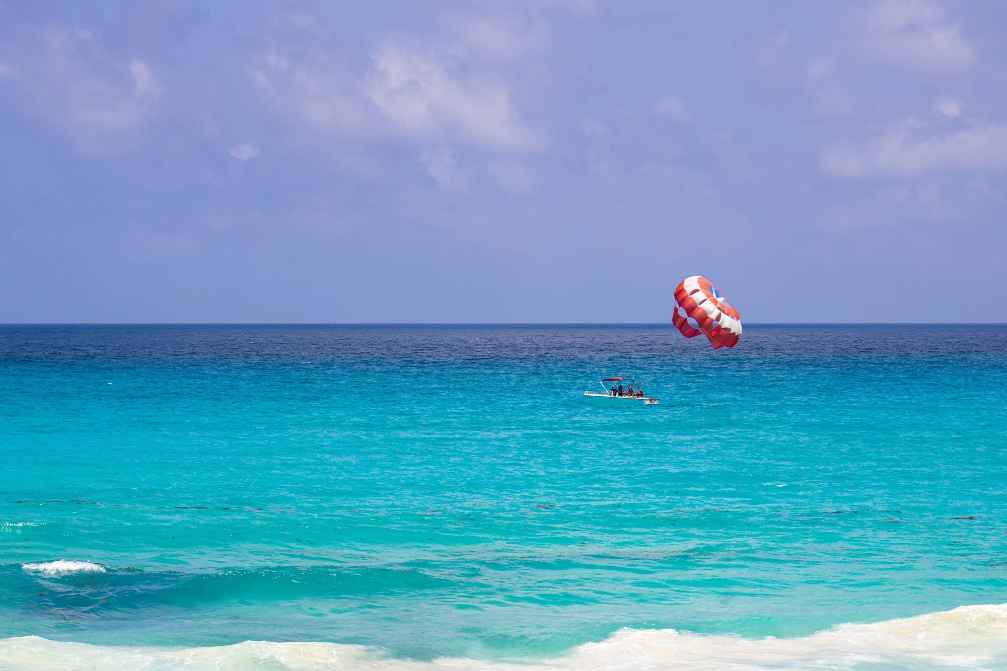 Parachute ascensionnel au-dessus de l'eau turquoise au large des plages de Cancún
