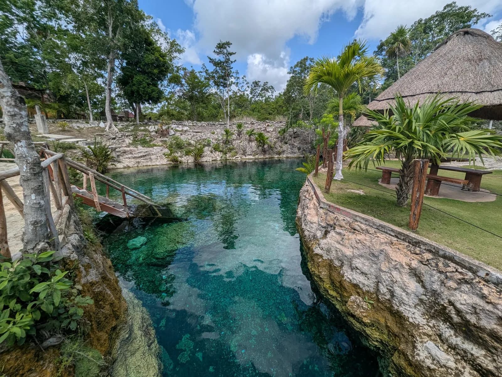 Cenote ouvert aux eaux turquoise entouré de jungle et de palapas près de Tulum, Riviera Maya