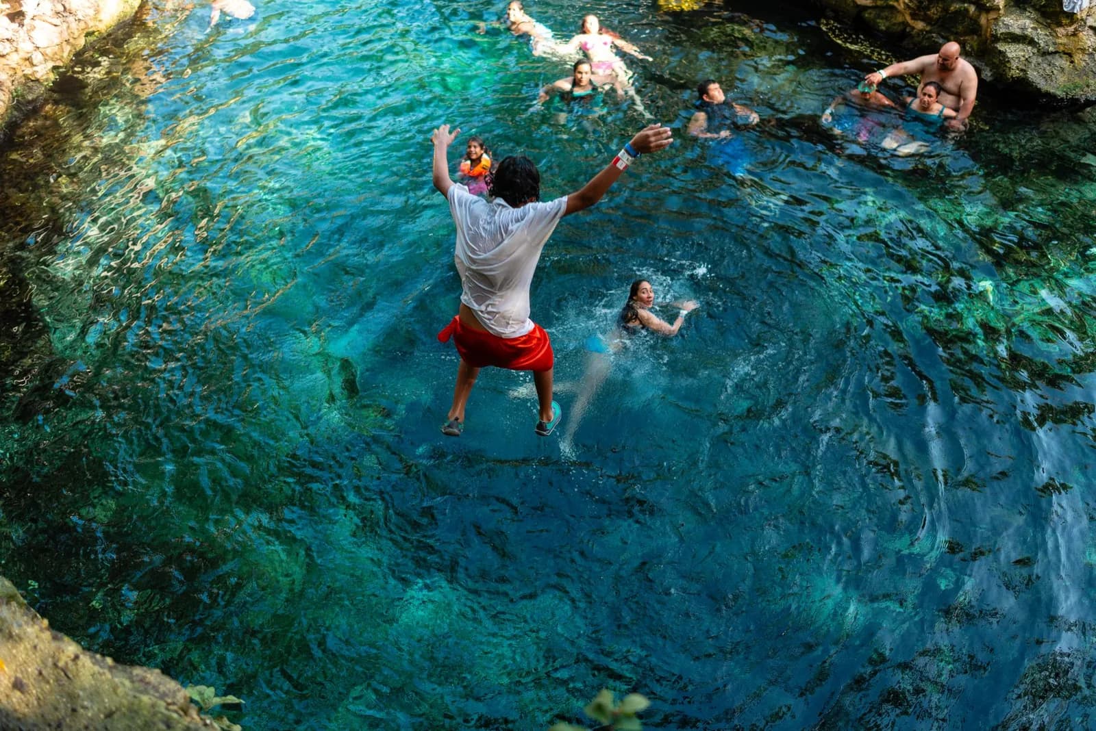 Baigneur sautant dans l'eau turquoise d'un cenote de la Riviera Maya