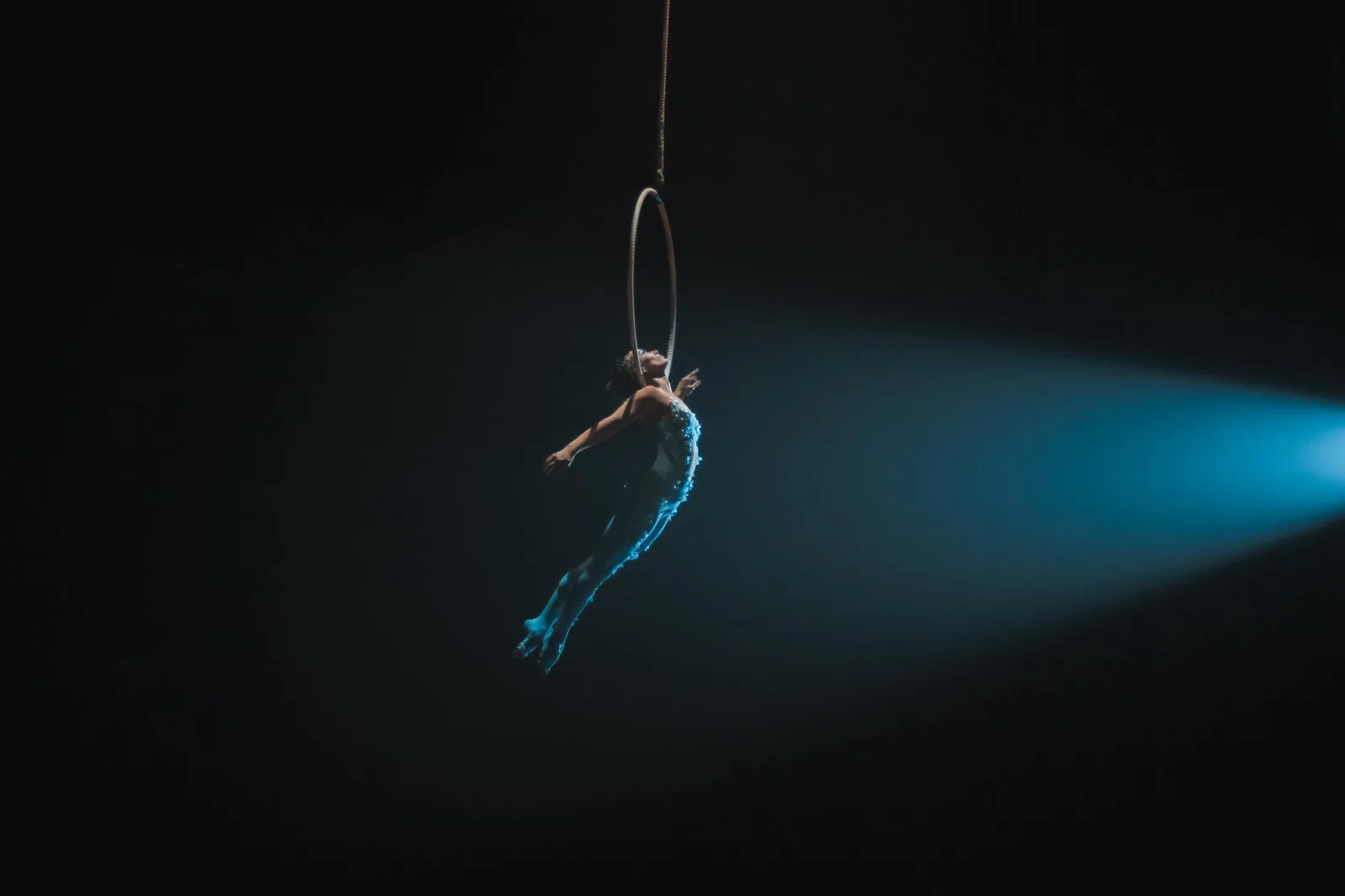 Acrobate aérienne sur cerceau sous un faisceau de projecteur, comme dans les numéros suspendus des shows de Cancún