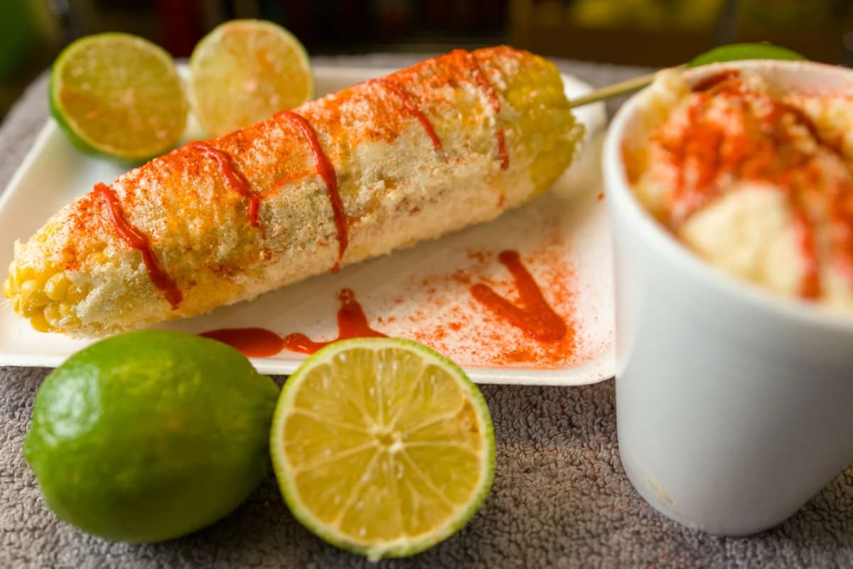 Elote mexicain au piment et au citron vert servi avec un gobelet d'esquites