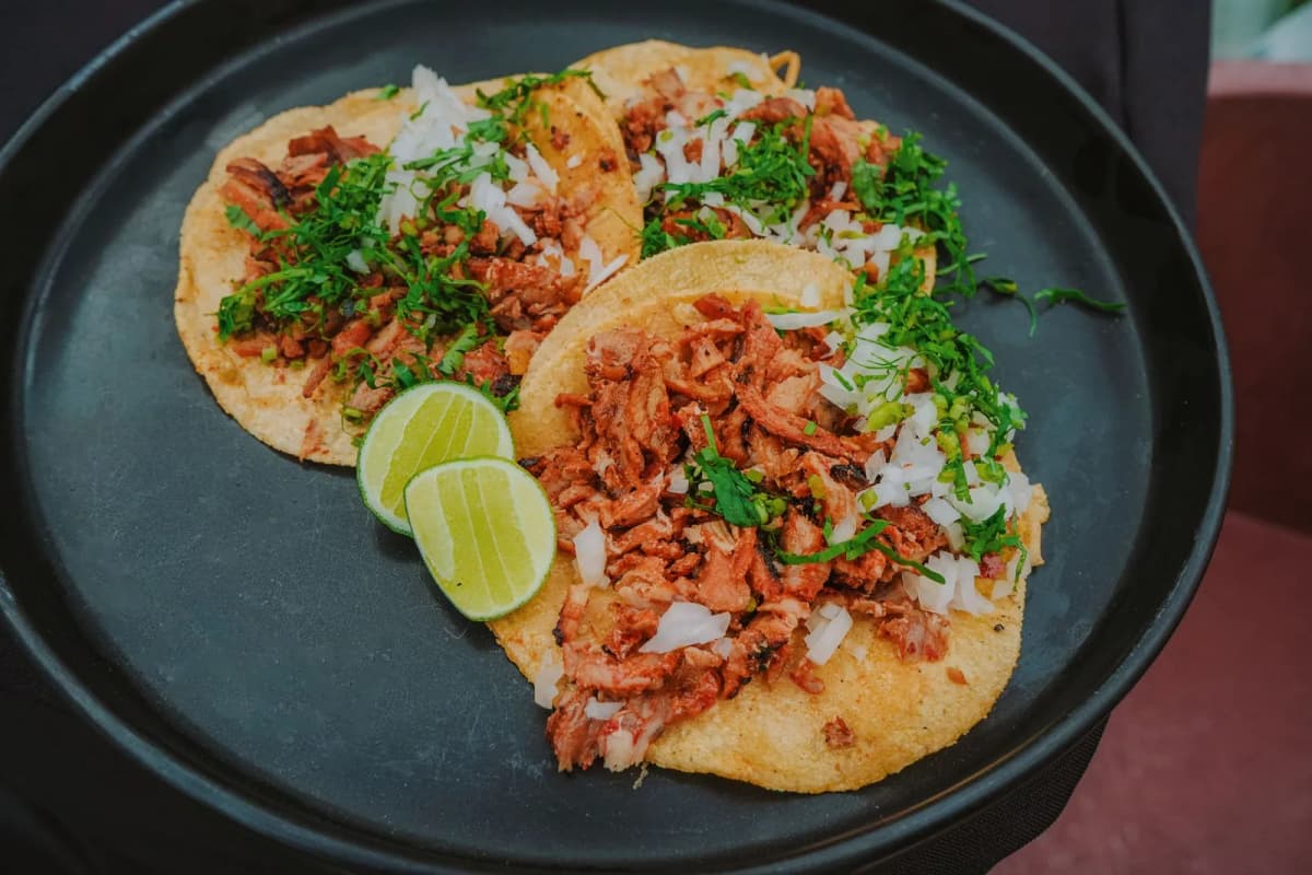 Trois tacos al pastor sur tortillas de maïs garnis d'oignon, coriandre et citron vert, Mexique