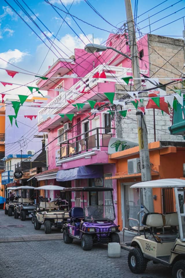 Golf carts colorés garés dans une rue du centre d'Isla Mujeres décorée de guirlandes