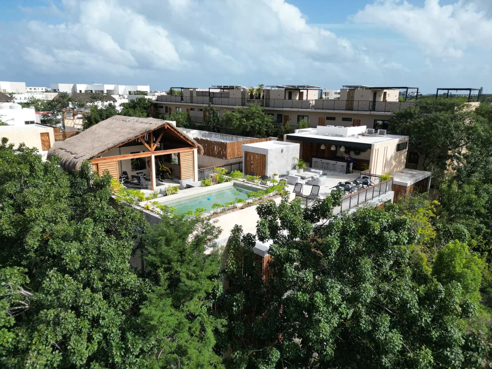 Vue aérienne d'une résidence avec piscine et terrasse en bois entourée de jungle, à Tulum