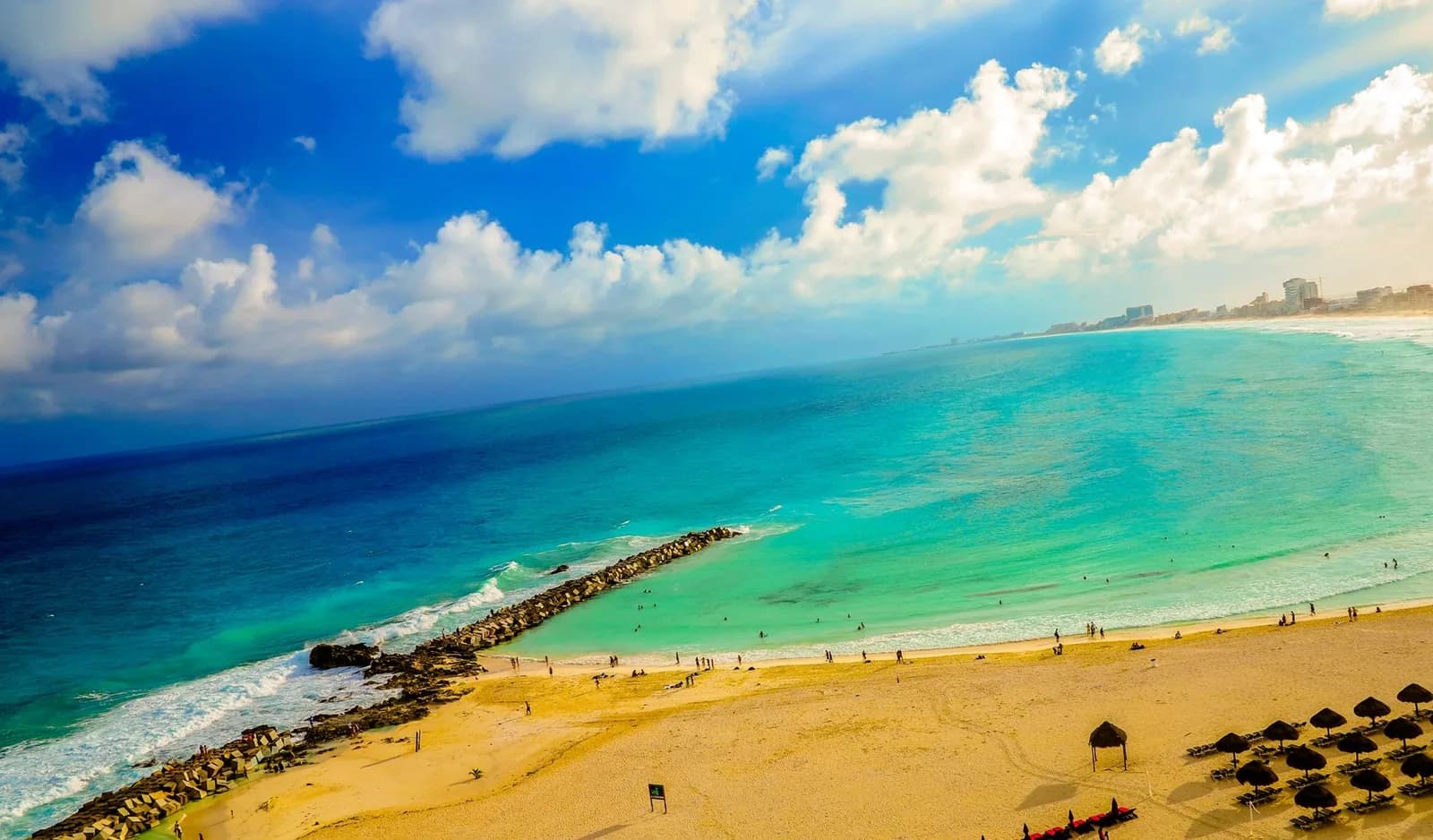 Eau turquoise peu profonde protégée par une digue de rochers sur une plage du nord de Cancún