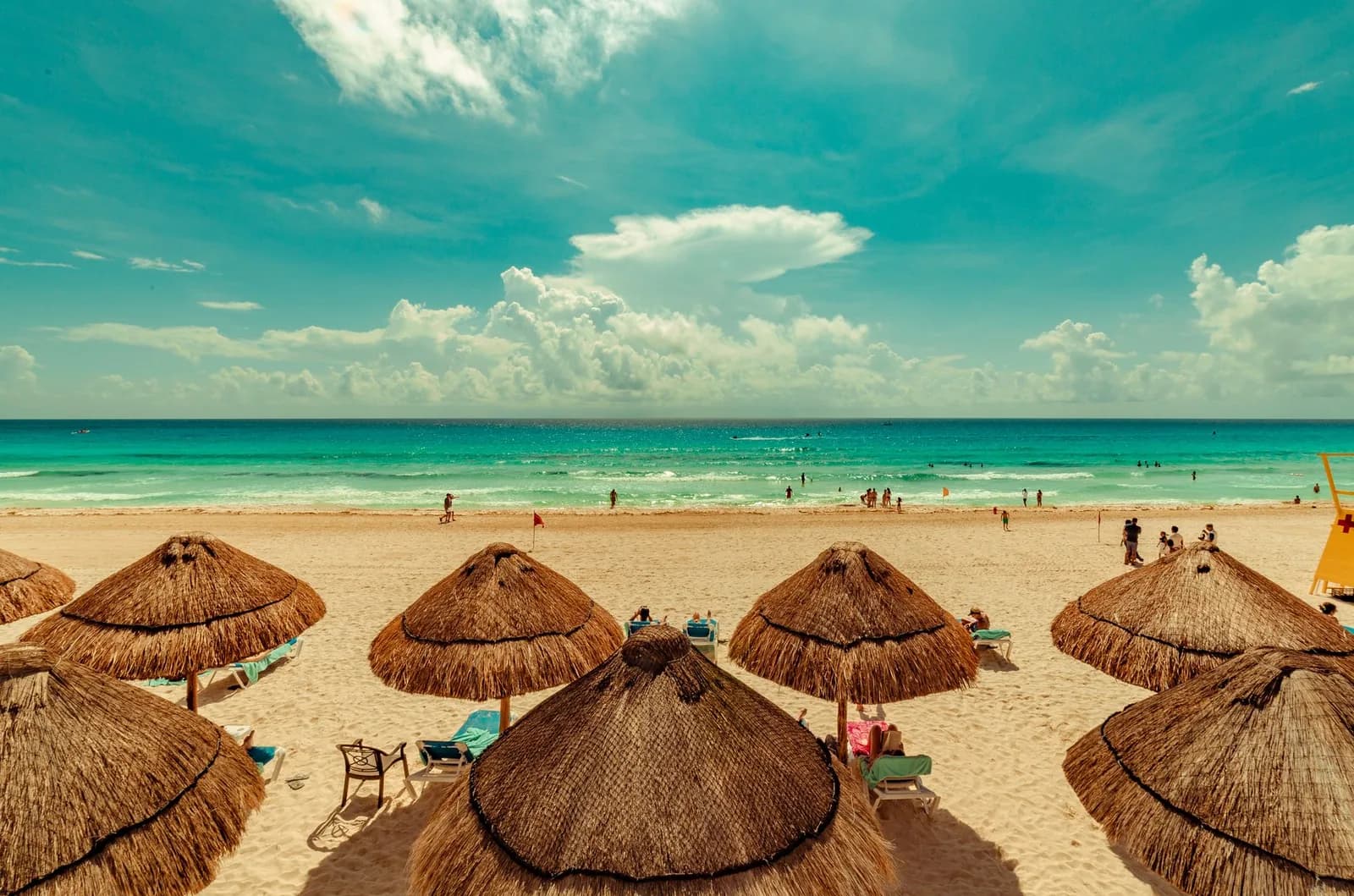 Palapas de paille et mer turquoise sur une plage de la zone hôtelière de Cancún, Mexique