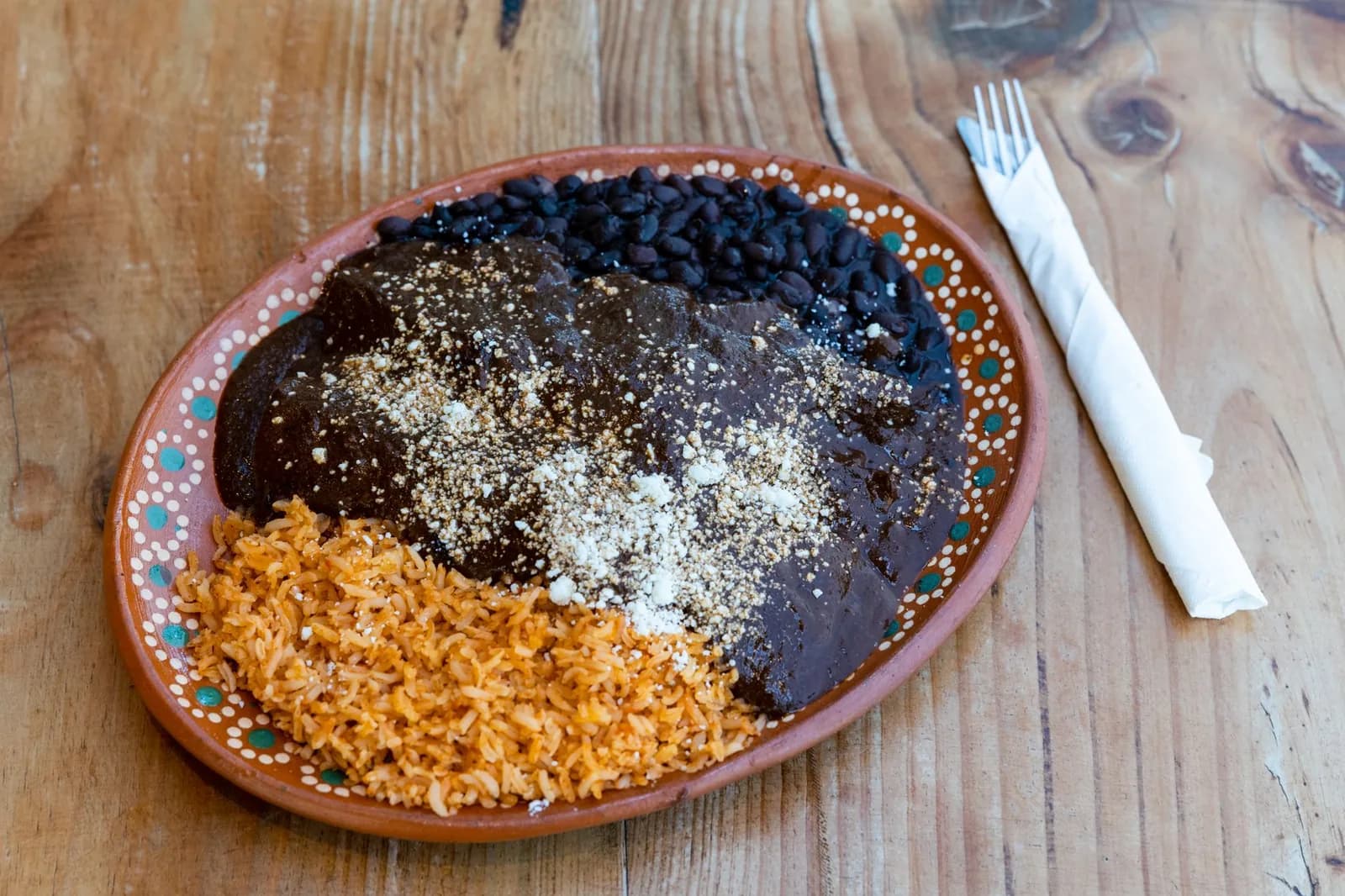 Assiette de mole poblano servie avec du riz rouge et des haricots noirs sur une poterie mexicaine, à Puebla