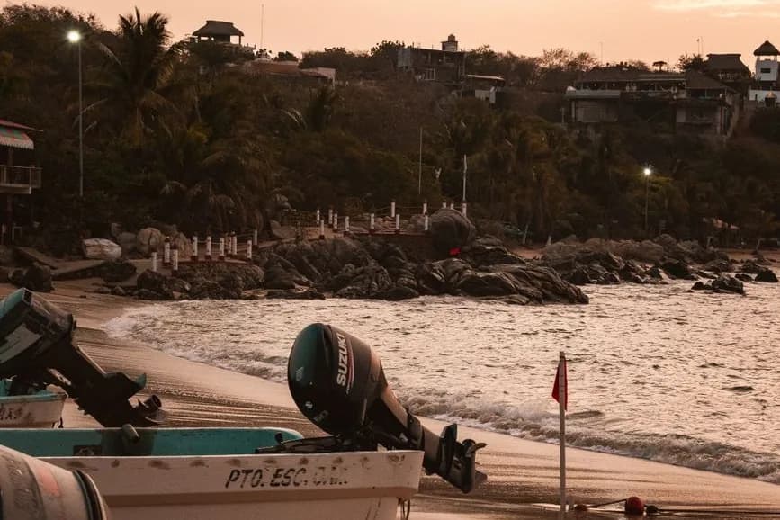 Lanchas de pêcheurs à moteur échouées sur le sable de Playa Principal à Puerto Escondido, au crépuscule