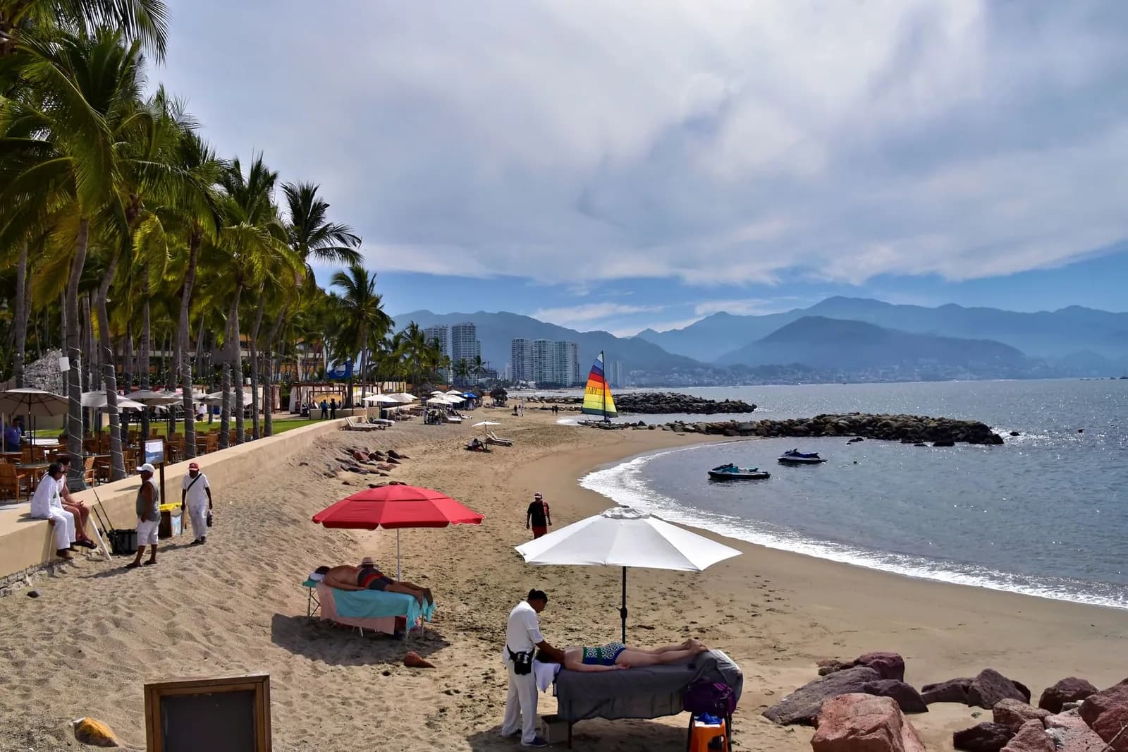 Plage bordée de palmiers à Puerto Vallarta avec la baie de Banderas et les montagnes de la Sierra Madre en arrière-plan