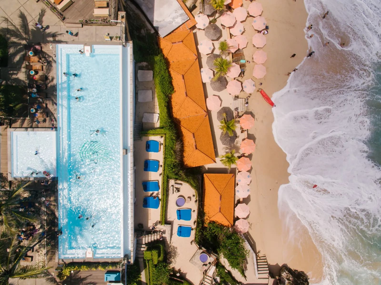 Vue aérienne d'un beach club avec piscine, transats et parasols en bord de mer des Caraïbes