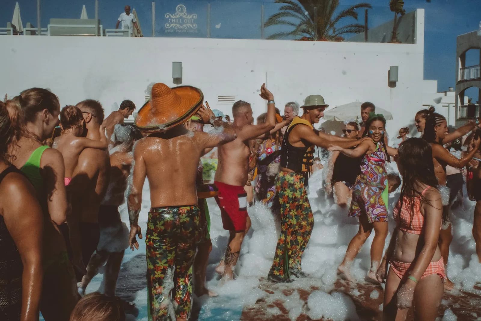 Foule dansant lors d'une pool party avec de la mousse au bord d'une piscine d'hôtel