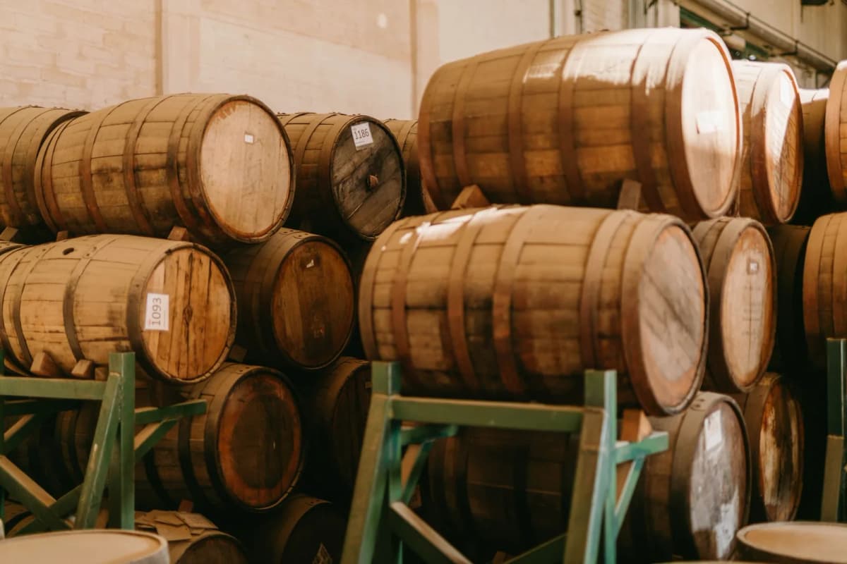 Fûts de chêne empilés sur des supports dans le chai d'une distillerie de tequila