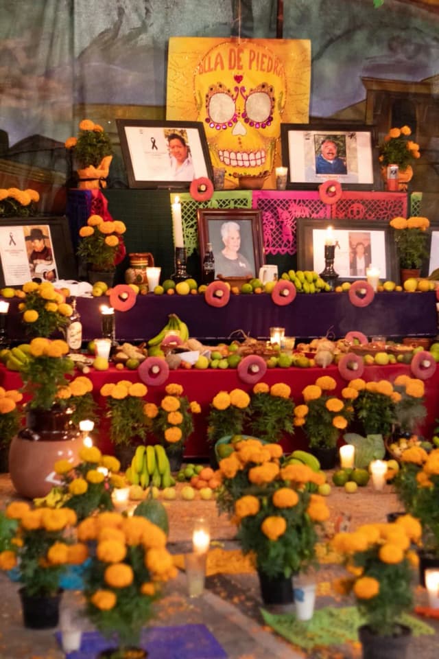 Ofrenda du Dia de Muertos couverte de fleurs de cempasúchil, bougies, photos des défunts et calavera en papier au Mexique