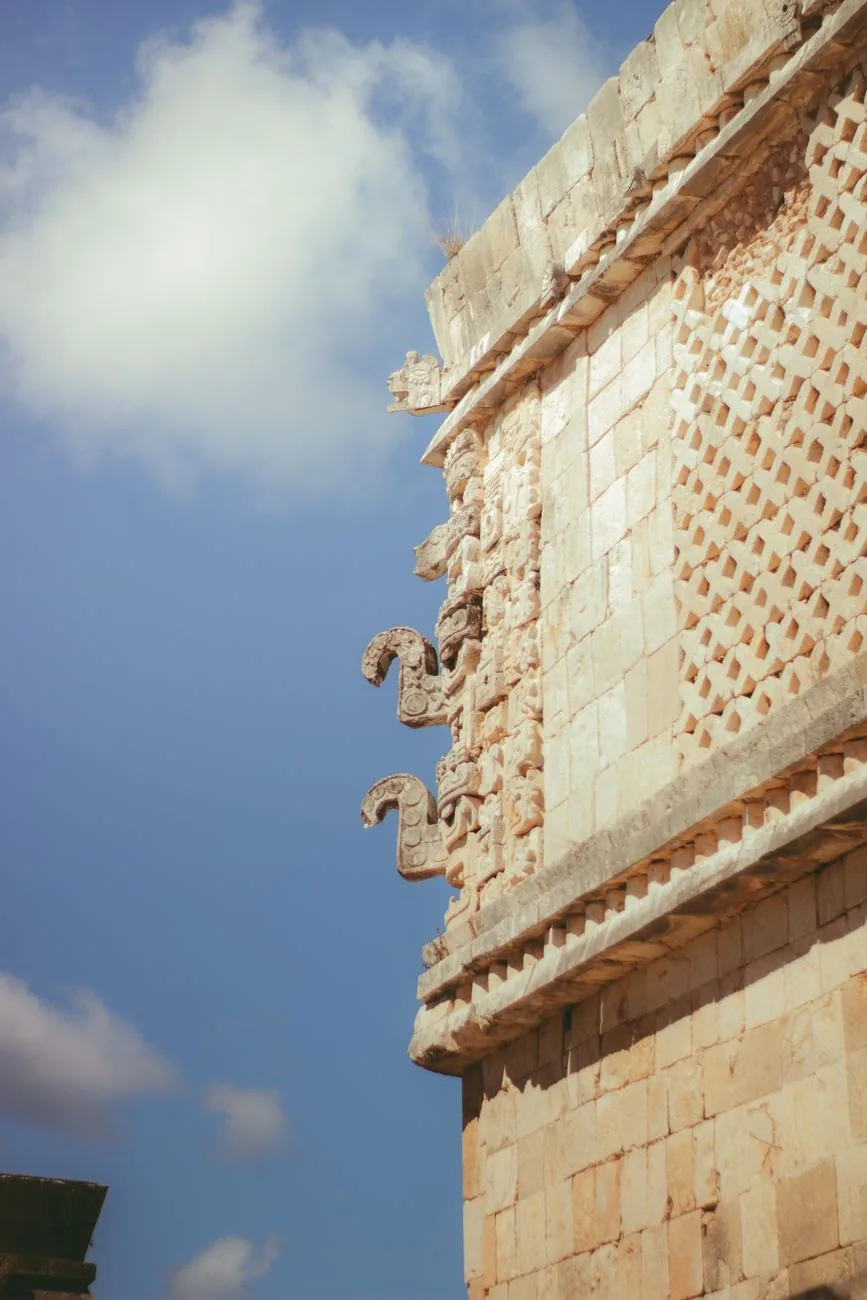 Frise de style Puuc à Uxmal : mur lisse en bas, treillis de pierre et nez crochus de Chaac en haut