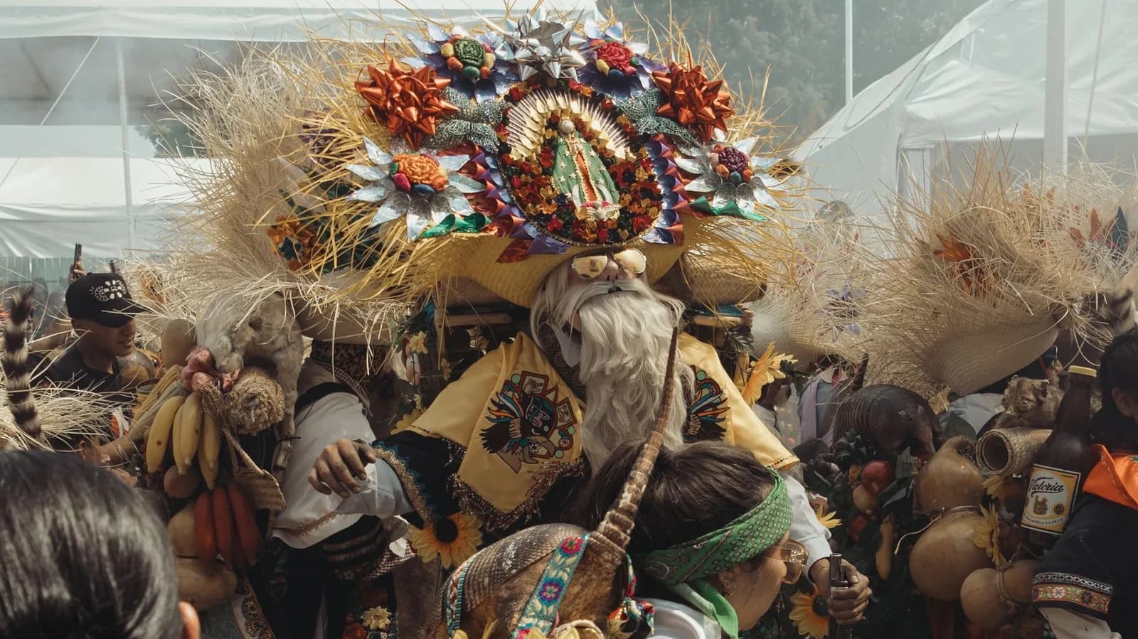 Danseur costumé portant une Vierge de Guadalupe sur sa coiffe au milieu d'une foule de pèlerins, lors d'une fête guadalupéenne au Mexique