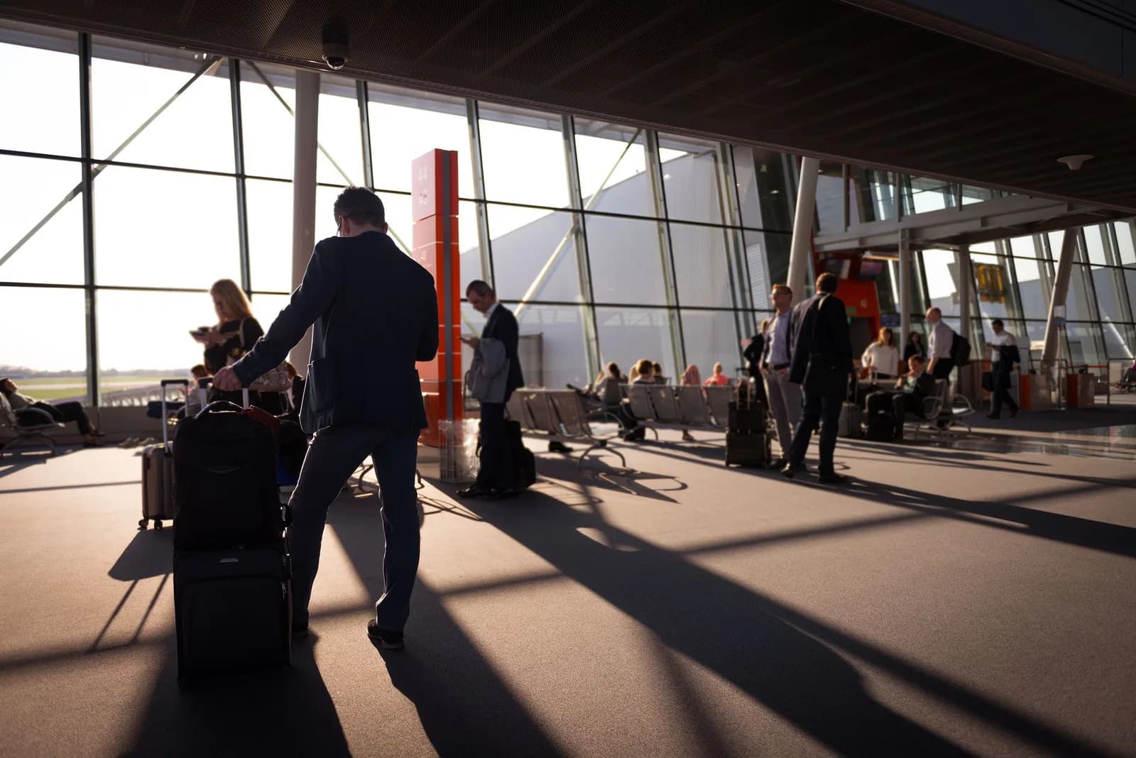 Voyageurs avec leurs valises dans le hall d'un aéroport, près de la zone d'embarquement