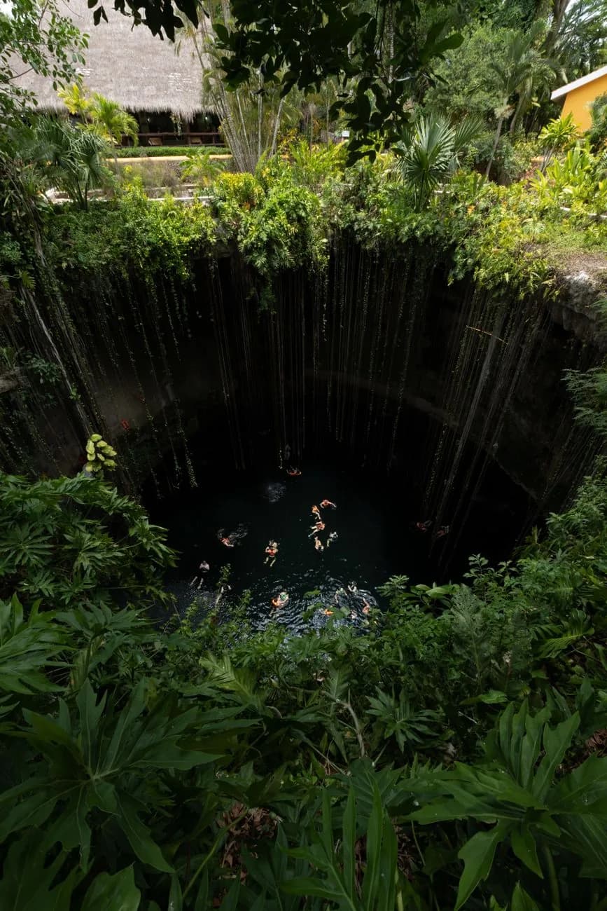 Baigneurs dans le cenote Ik Kil, puits naturel entouré de végétation, Yucatán